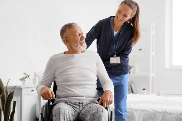 Starszy mężczyzna na wózku inwalidzkim z opiekunem w domu - Zdjęcie, obraz