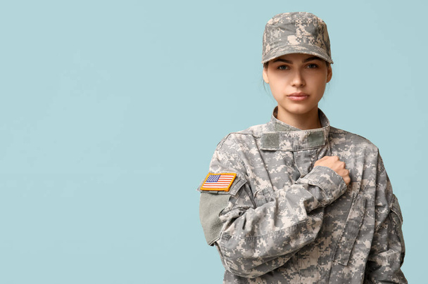 Jeune soldat confiante en uniforme saluant sur fond bleu - Photo, image