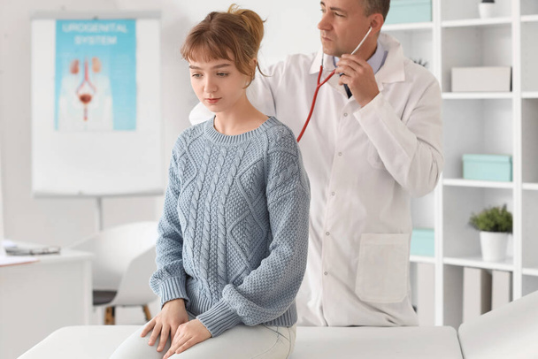 Зрелый врач, слышащий пациента со стетоскопом в медицинском кабинете - Фото, изображение
