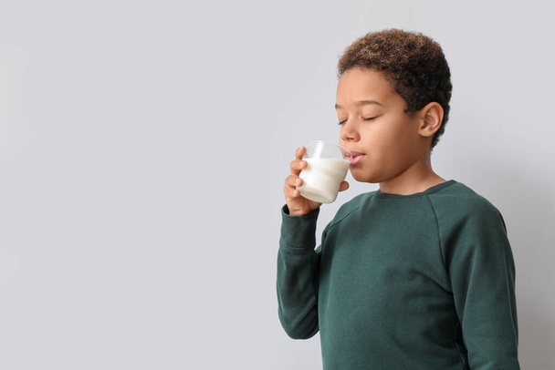 Kleine Afro-Amerikaanse jongen met glas melk op witte achtergrond - Foto, afbeelding
