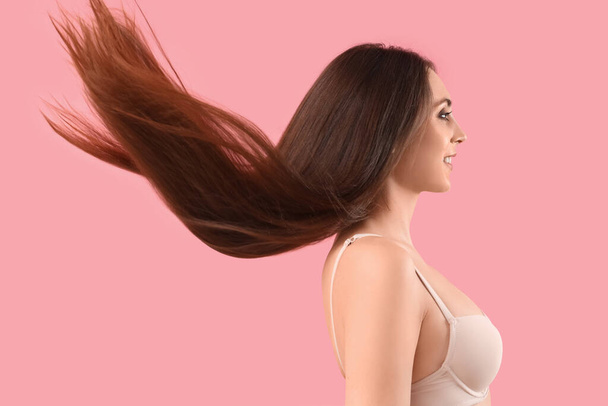 Young brunette woman with beautiful waving hair on pink background - Photo, Image