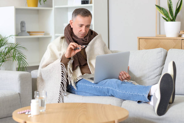 Enfermo hombre maduro mostrando termómetro al médico en línea en casa - Foto, Imagen