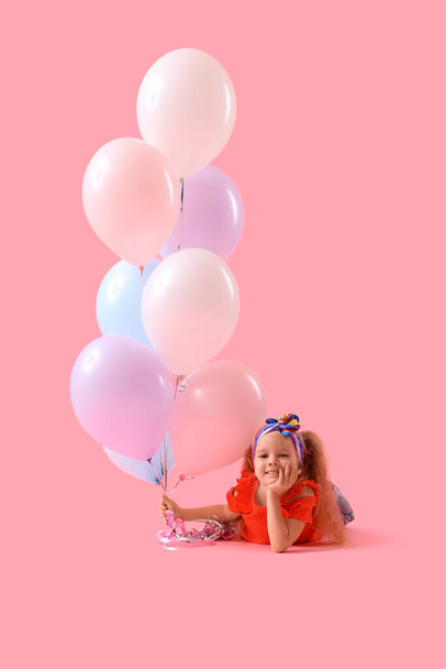Linda niña con hermosos globos tumbados sobre fondo rosa - Foto, imagen