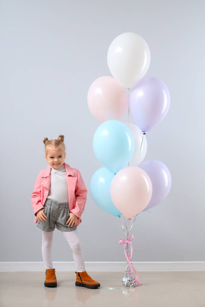 Χαριτωμένο κοριτσάκι με όμορφα μπαλόνια κοντά σε γκρι τοίχο - Φωτογραφία, εικόνα