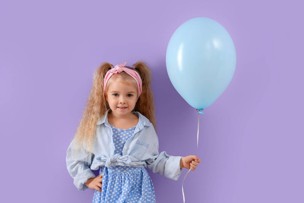 Χαριτωμένο κοριτσάκι με όμορφο μπαλόνι σε μωβ φόντο - Φωτογραφία, εικόνα