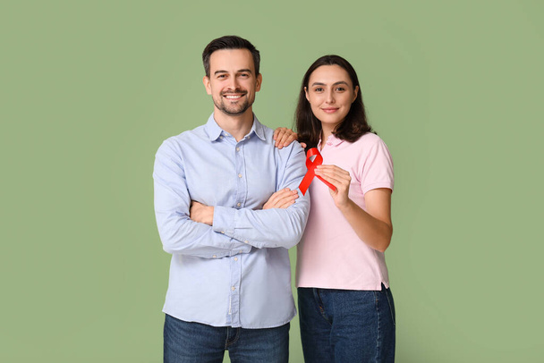 Lovely couple with red ribbon on green background. World AIDS Day concept - Photo, Image