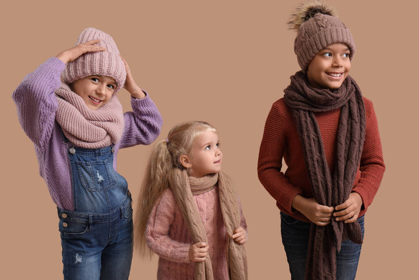 Roztomilé děti v zimním oblečení na béžovém pozadí - Fotografie, Obrázek