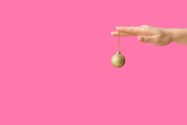 Mano femenina con bola de Navidad sobre fondo rosa - Foto, Imagen