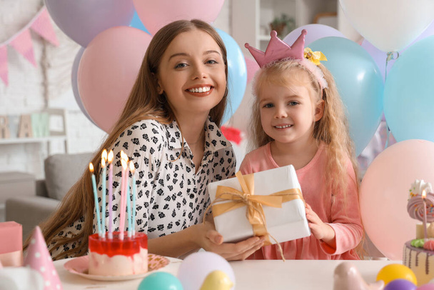 Niedliches kleines Mädchen in Krone erhält Geburtstagsgeschenk von ihrer Mutter zu Hause - Foto, Bild