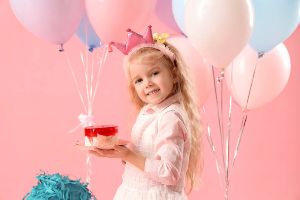 Cute little girl in crown with Birthday cake and balloons on pink background - Photo, Image