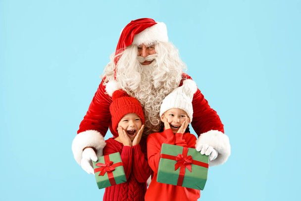Zaskoczony małe dzieci otrzymujące prezenty świąteczne od Świętego Mikołaja na niebieskim tle - Zdjęcie, obraz