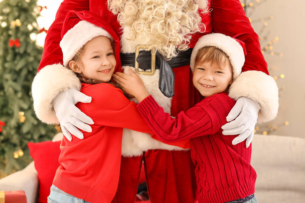 Bambini piccoli e carini che abbracciano Babbo Natale a casa la vigilia di Natale - Foto, immagini