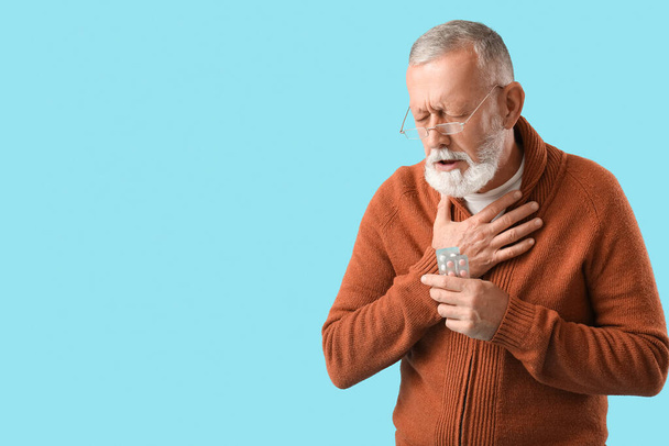 Больной взрослый мужчина с таблетками на синем фоне - Фото, изображение
