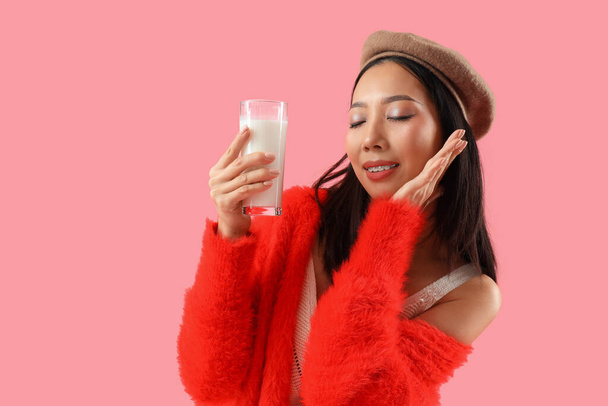 Mladá asijská žena se sklenicí mléka na růžovém pozadí - Fotografie, Obrázek