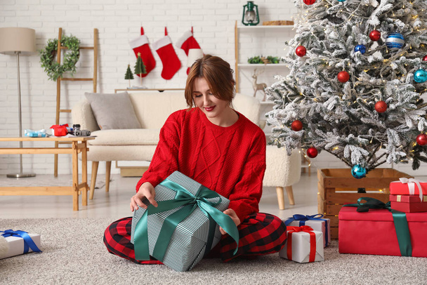 Hermosa mujer joven con cajas de regalo sentado en la habitación decorada para Navidad - Foto, imagen