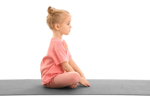 Linda niña con esterilla practicando yoga aislada sobre fondo blanco - Foto, Imagen