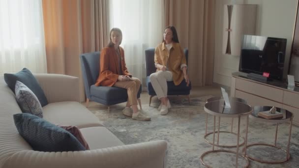 Zoom laukaus naispuolinen asiakaspalvelu avustaja ja mahdollinen ostaja istuu nojatuolit mock-up olohuone huonekaluliike - Materiaali, video