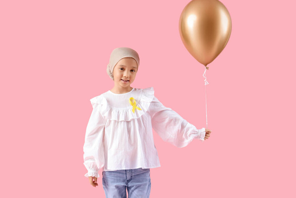 Pieni aasialainen tyttö jälkeen kemoterapia nauha ja ilmapallo vaaleanpunainen tausta. Lapsuuden syöpätietoisuuden käsite - Valokuva, kuva