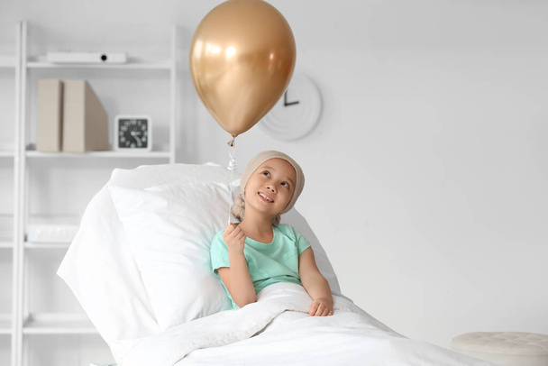 Little Asian girl after chemotherapy with balloon lying in clinic. Childhood cancer awareness concept - Photo, Image