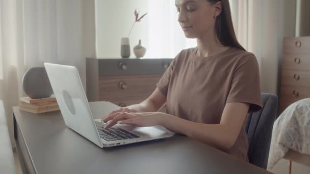 Colpo medio di giovane donna caucasica seduta nel suo studio dietro il desktop, che lavora in remoto sul computer portatile - Filmati, video