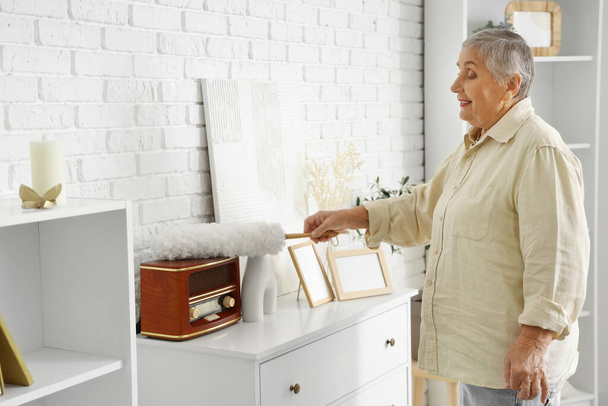 Старша жінка прибирає радіоприймач з pp-шустером вдома - Фото, зображення