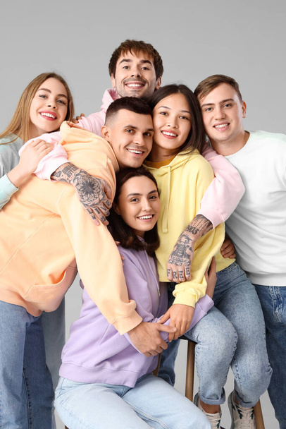 Groep stijlvolle jongeren knuffelen op lichte achtergrond - Foto, afbeelding