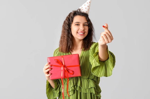 Piękna młoda kobieta w kapeluszu party z pudełka z okazji urodzin na szarym tle - Zdjęcie, obraz