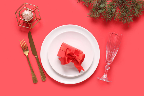 Όμορφη ρύθμιση τραπέζι με κλαδιά χριστουγεννιάτικο δέντρο, κουτί δώρου και κερί σε κόκκινο φόντο - Φωτογραφία, εικόνα