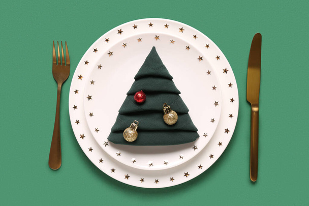 Schöne Tischdekoration mit Weihnachtskugeln auf grünem Hintergrund - Foto, Bild