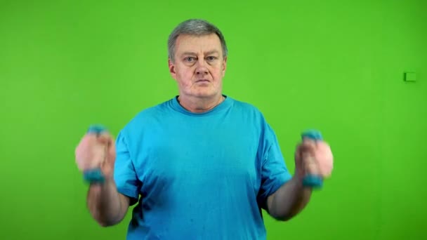 Senior man doing dumbbells exercise daily workout, lifts arms up to shoulders. Mature person doing sport or exercise for maintaining health. Green screen. Chroma key. - Footage, Video