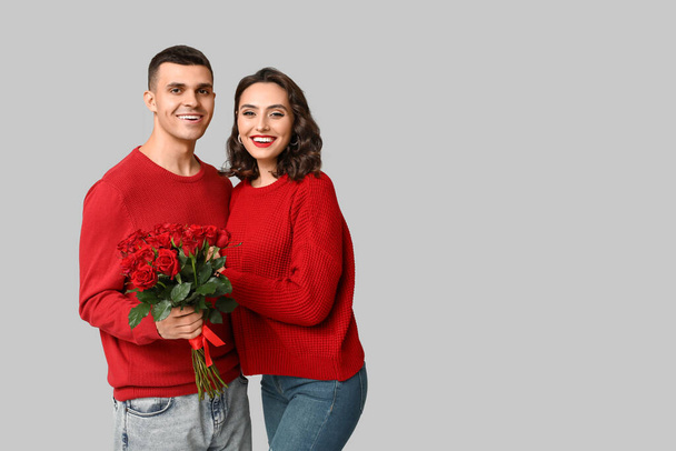 緑の背景に美しいバラの花束を持つ若いカップルを愛する. 聖バレンタインデーのお祝い - 写真・画像