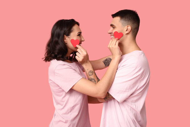 Αγαπημένο νεαρό ζευγάρι με χάρτινες καρδιές σε ροζ φόντο. Εορτασμός της ημέρας του Αγίου Βαλεντίνου - Φωτογραφία, εικόνα