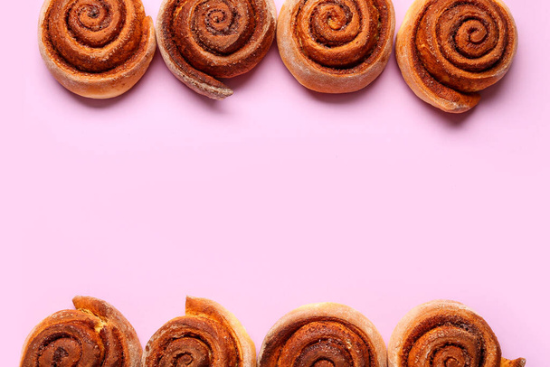 Frame made of tasty cinnamon rolls on lilac background - Photo, Image