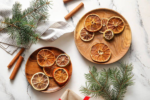 Platos de madera con rodajas secas de naranja y canela sobre fondo blanco - Foto, imagen