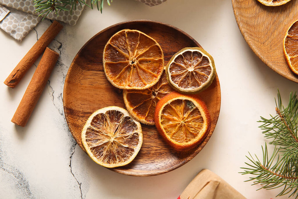 Wooden plate with dried orange slices and cinnamon on white background - Photo, Image