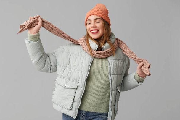 Gyönyörű fiatal boldog nő meleg téli ruhák szürke háttér - Fotó, kép