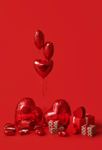 Μπαλόνια αέρα σε σχήμα καρδιάς και κουτιά δώρων σε κόκκινο φόντο - Φωτογραφία, εικόνα