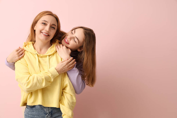 Hermosa mujer joven abrazando a su madre sobre fondo rosa. Día Internacional del Abrazo - Foto, Imagen