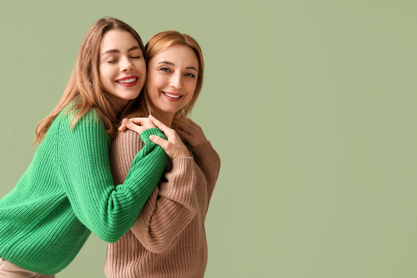 Счастливая молодая женщина обнимает свою мать на зеленом фоне. Международный день объятий - Фото, изображение