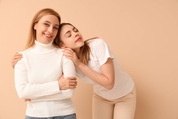 Beautiful young woman hugging her mother on beige background. International Hug Day - Photo, Image