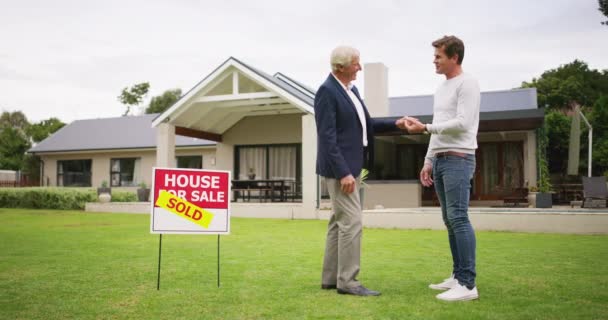 Man, real estate keys and outdoor with hand shake for agreement, deal and congratulations on sale. Men, property and shaking hands on grass with investment, mortgage and new house in neighborhood. - Footage, Video