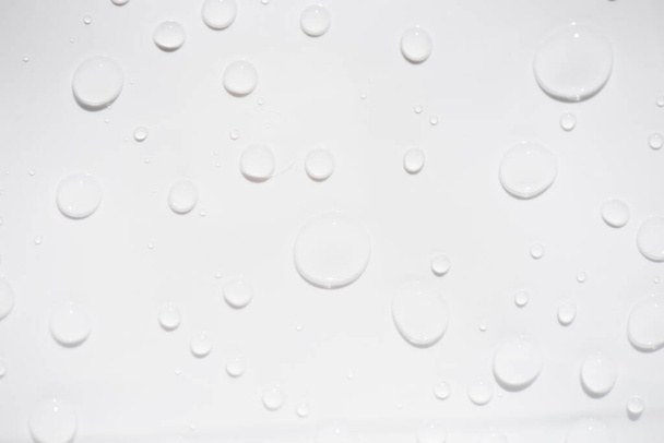 water druppels op wit. Witte waterbellen op het oppervlak rimpelen. Defocus wazig transparant wit-zwart gekleurde heldere kalme water oppervlak textuur met spatten en bellen. Watergolven schijnen. - Foto, afbeelding