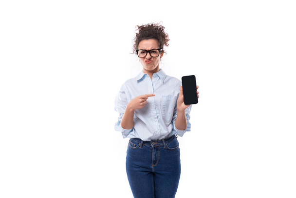 розумна молода брюнетка кучерявий менеджер жінка в окулярах для зображення демонструє смартфон з маком. - Фото, зображення