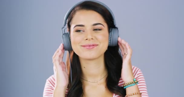 Music, headphones and face of happy woman in studio with podcast, track and good mood on grey background. Portrait, earphones and female smile for radio, streaming or subscription to online audio. - Footage, Video