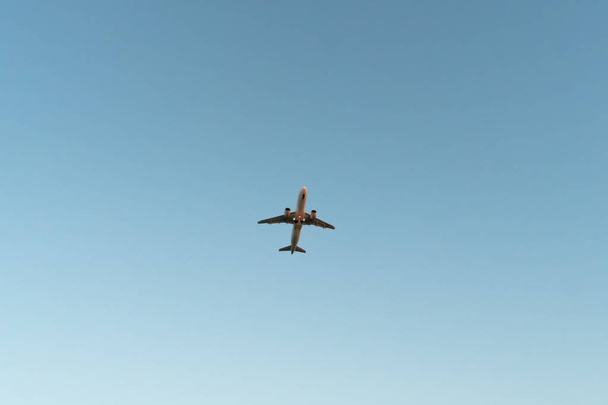 Zbliżenie białego samolotu startującego na błękitne niebo, widok z dołu. Podróż samolotem - Zdjęcie, obraz