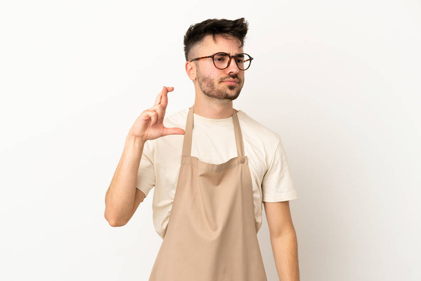 Serveur restaurant homme caucasien isolé sur fond blanc avec les doigts croisés et souhaitant le meilleur - Photo, image