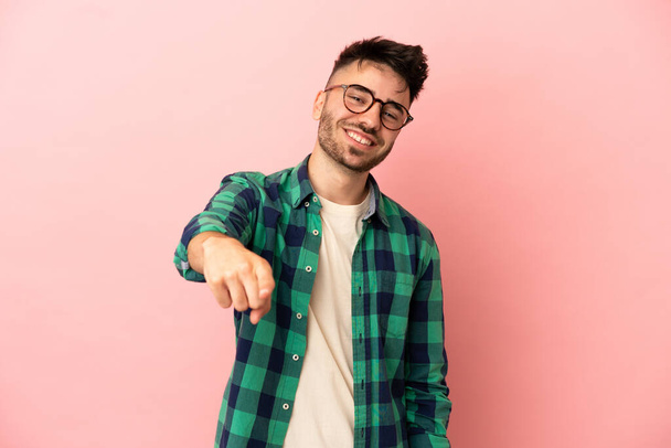 Young caucasian man isolated on pink background pointing front with happy expression - Photo, Image