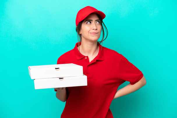 Pizza donna consegna con uniforme di lavoro raccogliendo scatole di pizza isolate su sfondo blu e guardando in alto - Foto, immagini