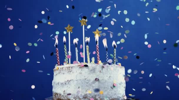 Célébration de gâteau d'anniversaire, bougies et confettis tombant au ralenti sur fond bleu - Séquence, vidéo