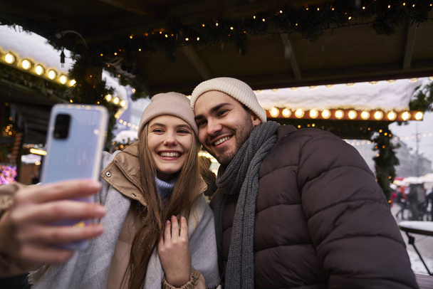 Mladý pár se selfie na vánočním trhu v noci - Fotografie, Obrázek